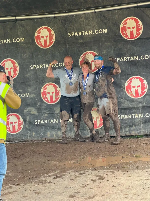 Corey and Kayla on the Spartan race podium, covered in mud