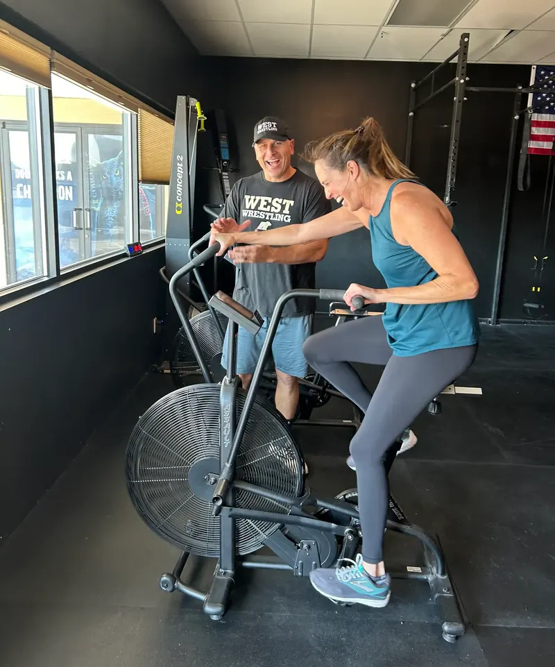 A coach encouraging a member through a set on the assault bike