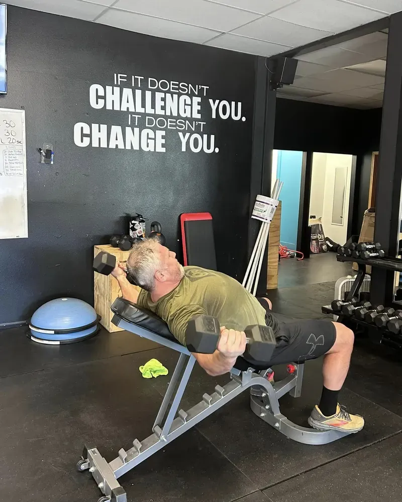 A longtime member pressing dumbbells on an incline bench